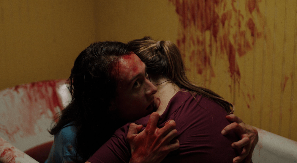 two people hug in a bathtub filled with blood