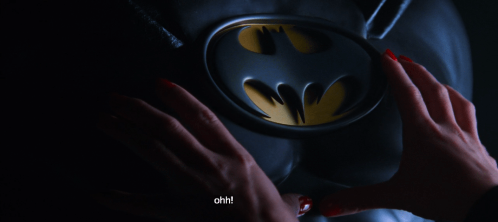 a woman's hands touch the front of the Batman suit