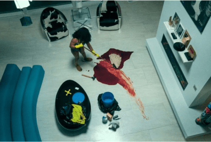 an overhead shot of a young woman mopping up a large amount of blood on the floor