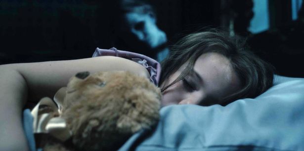 a girl sleeping with a teddy bear as a ghost looks on