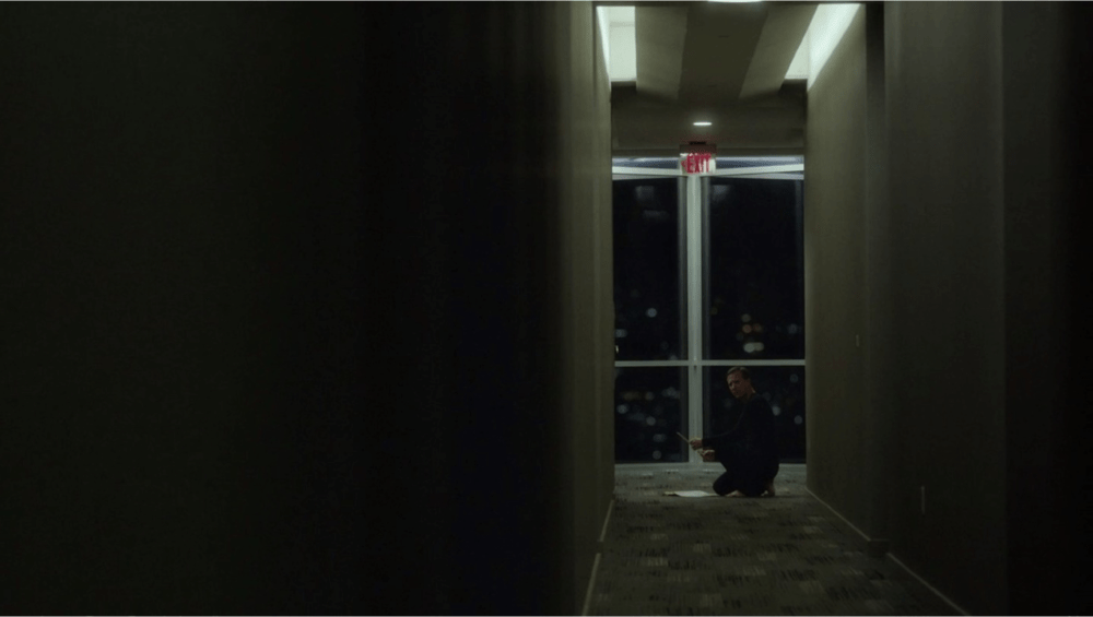 a distance shot showing someone kneeling at the end of a hallway