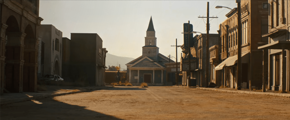 a desolate town with a church steeple in the distance