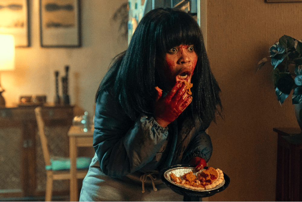 a young woman eats pie with her hands. Her face shows blood stains.