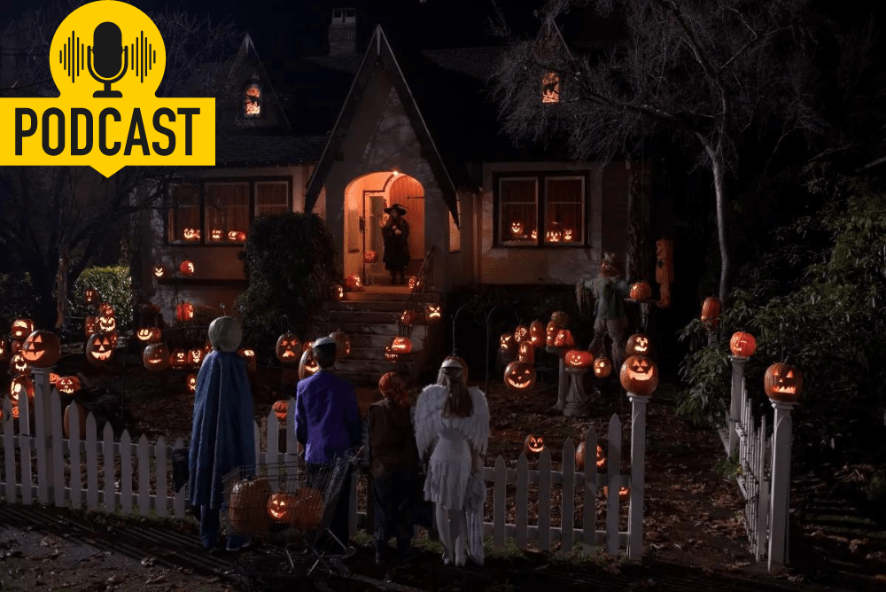 A group of kids dressed in Halloween costumes talk to a girl dressed as a witch who is standing on her porch and is surrounded by many lit pumpkins.